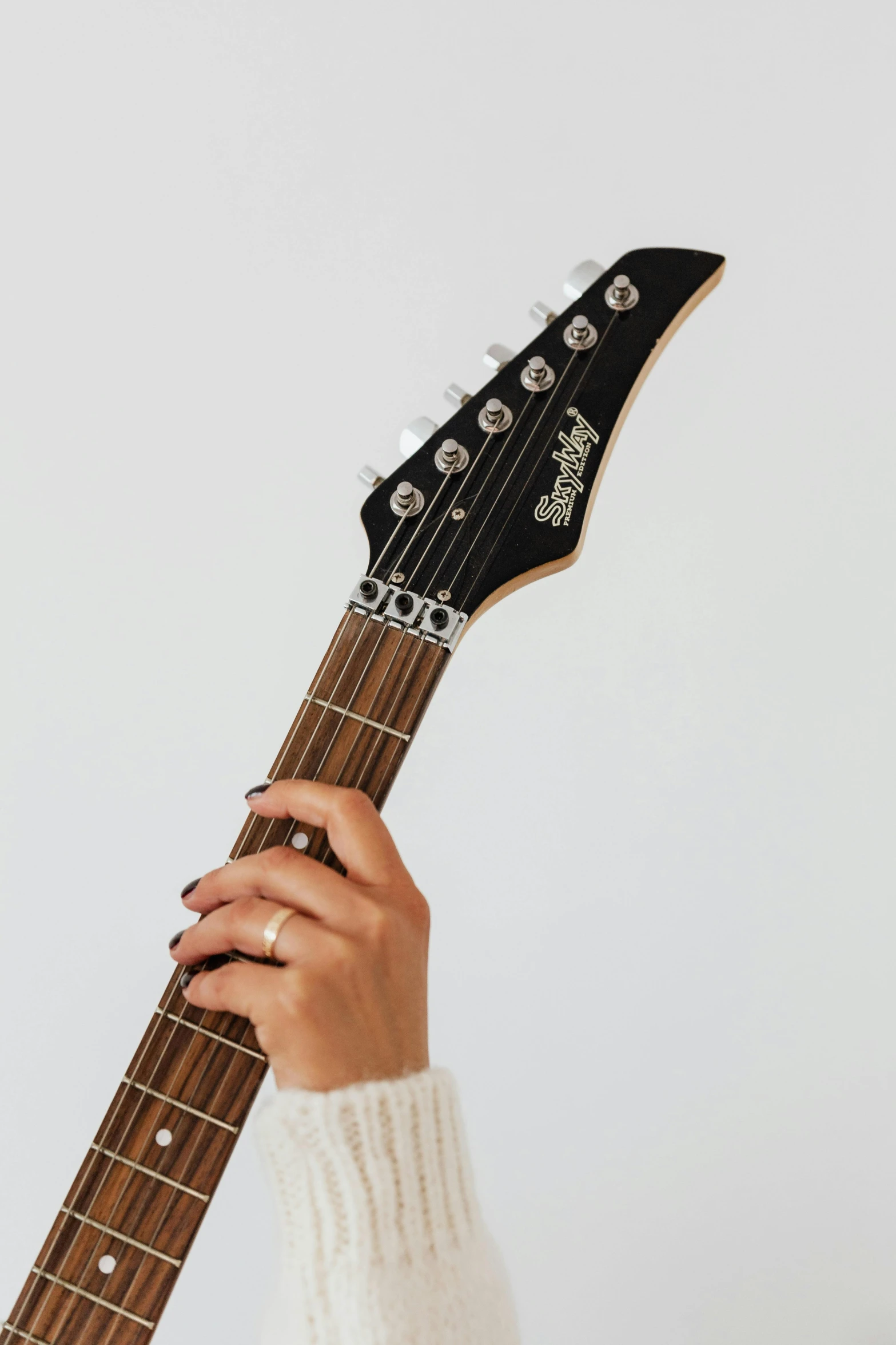 a woman holding a guitar up to her face, trending on pexels, plain background, high detail of a hand, johnny silverhand, view from ground