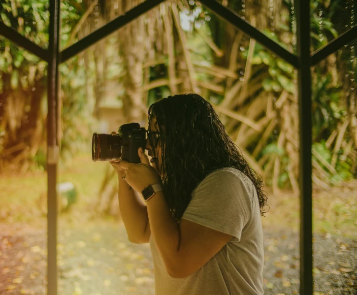 a woman holding a camera in front of a window, a picture, in a jungle environment, high-quality dslr photo”, avatar image, photographs