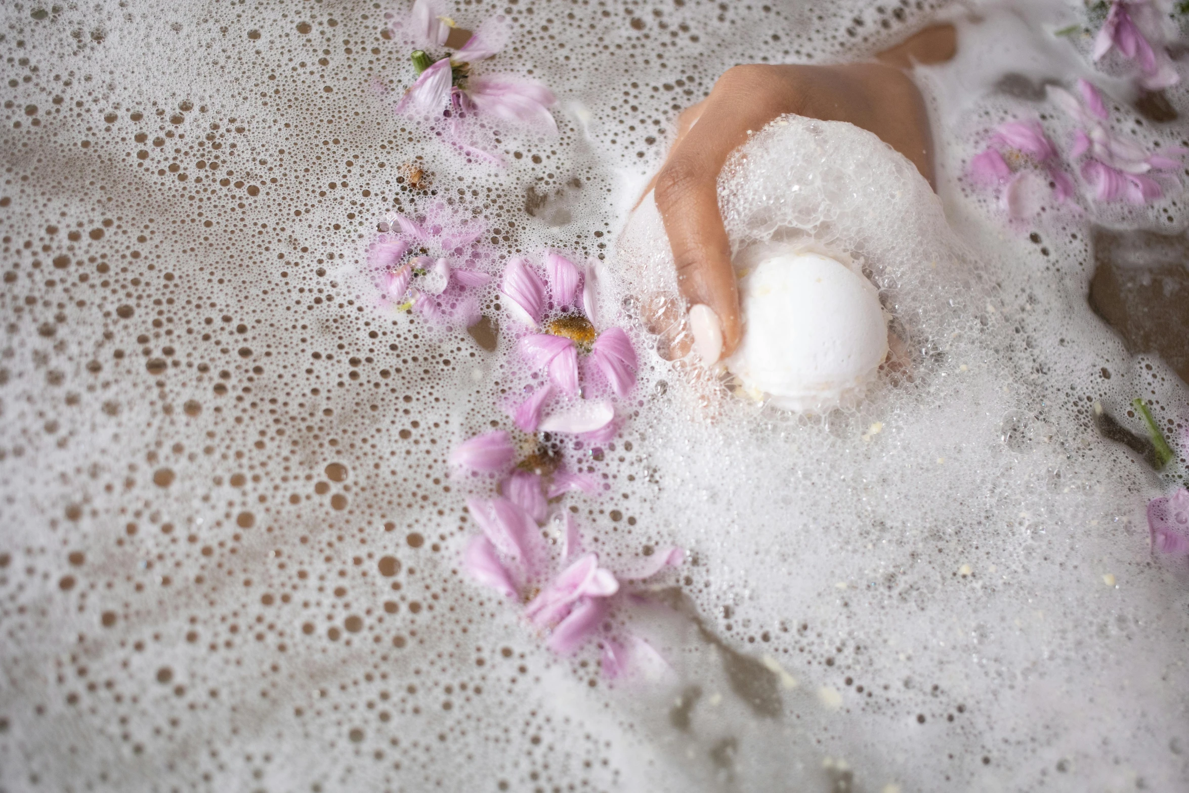 a close up of a person's hand in a foamy bath, trending on pexels, blossoms, a woman holding an orb, promo image, manuka