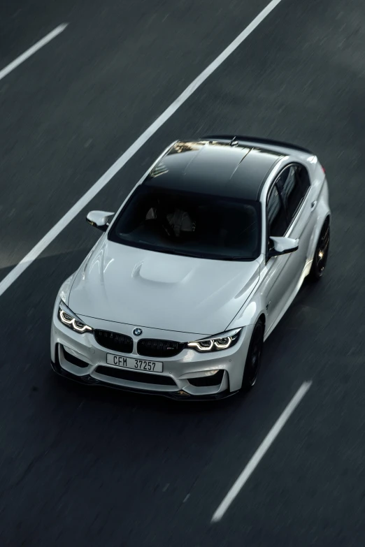 a white bmw car driving down a highway, a 3D render, inspired by Jan Kupecký, pexels contest winner, dramatic lighting from above, matt white color armor, front profile, high angle