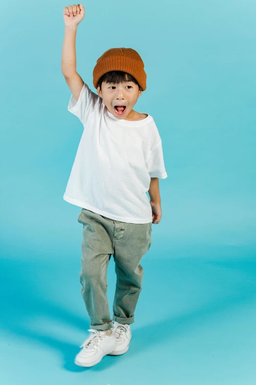 a young boy in a white t - shirt and khaki pants, a colorized photo, inspired by Reuben Tam, pexels, cute hats, solid background, excited, cute:2