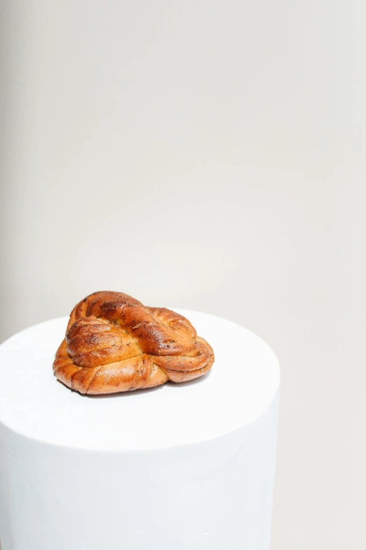 a croissant sitting on top of a white pedestal, by Nina Hamnett, perfectly symmetrical, vine twist, hip-length, nordic