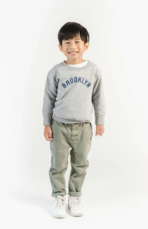 a young boy standing in front of a white background, inspired by Peter Rockwell, trending on unsplash, wearing sweatshirt, brooklyn background, official store photo, wearing pants