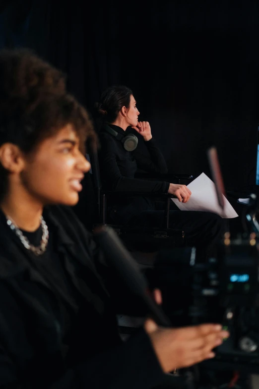 a group of people sitting next to each other on a stage, by Nina Hamnett, looking at monitor, imaan hammam, studio level quality, woman in black robes