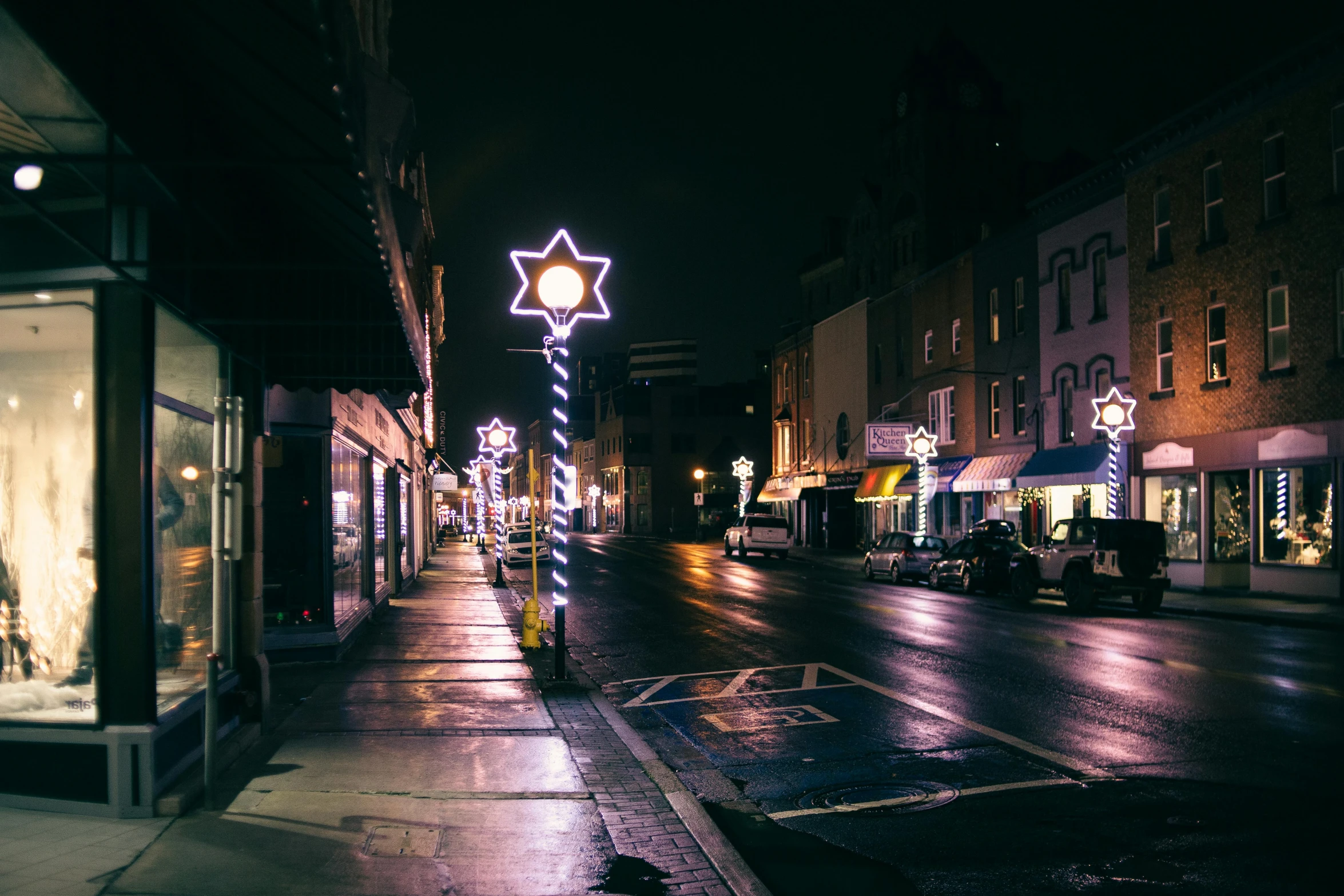 a city street is lit up with christmas lights, a photo, by Adam Rex, unsplash contest winner, star rain, square, midwest town, white neon lighting