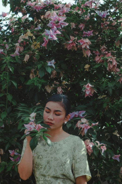 a woman standing in front of a bush of flowers, unsplash, aestheticism, indonesia, pastel green, lily, portrait”