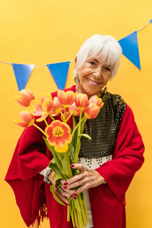 an older woman holding a bouquet of tulips, inspired by Eva Gonzalès, with yellow cloths, bright white hair, confetti, wearing a barca cape