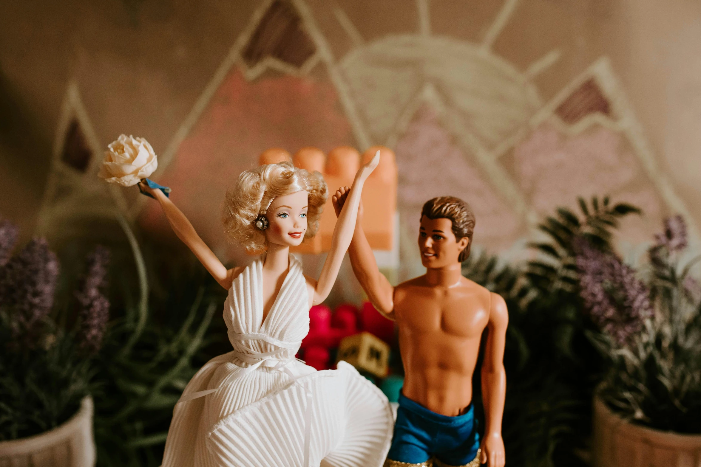 a couple of figurines sitting next to each other, an album cover, by Carey Morris, trending on unsplash, barbie or ken doll, white skirt and barechest, waving, bouquet