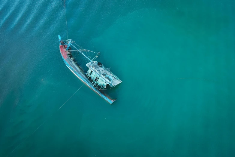 a small boat floating on top of a body of water, by Andries Stock, pexels contest winner, hurufiyya, dredged seabed, cyan, fishing, air shot