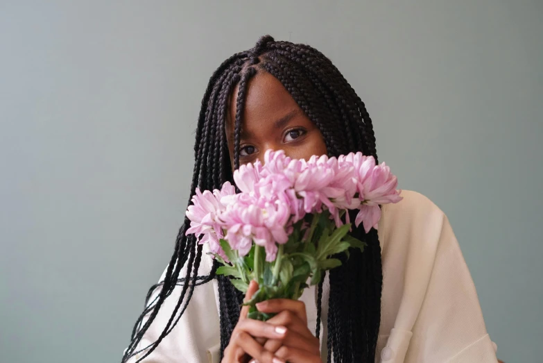 a woman holding a bunch of flowers in front of her face, by Dulah Marie Evans, pexels contest winner, hyperrealism, box braids, black teenage girl, lulu chen, mid length portrait photograph