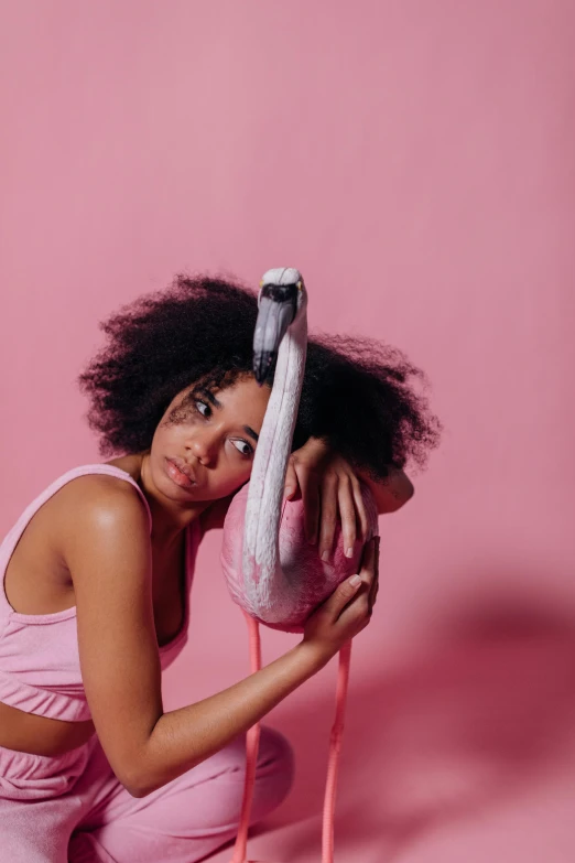 a woman sitting on the ground holding a stuffed animal, an album cover, pexels contest winner, flamingo, with afro, studio shoot, ((pink))