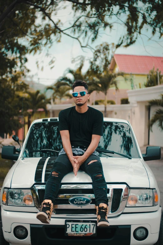 a man sitting on the hood of a white truck, an album cover, by Robbie Trevino, pexels contest winner, joseph moncada, real trending on instagram image, avatar image, black car