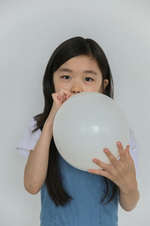 a little girl holding a white balloon in front of her face, inspired by Kanō Naizen, pexels contest winner, plain background, profile image, science, round jaw