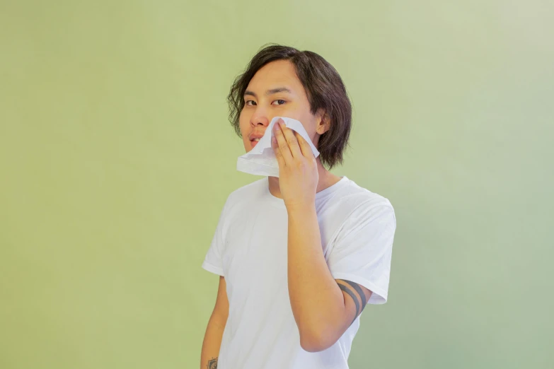 a man blowing his nose while standing in front of a green wall, inspired by Russell Dongjun Lu, pexels contest winner, smooth translucent white skin, telegram sticker, on a pale background, wearing translucent sheet