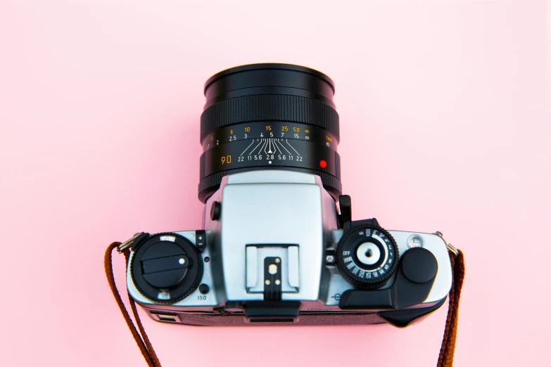 a camera sitting on top of a pink surface, a picture, looking up at camera, 35mm f/1.4l lens, reflective lens, 8 0 s camera