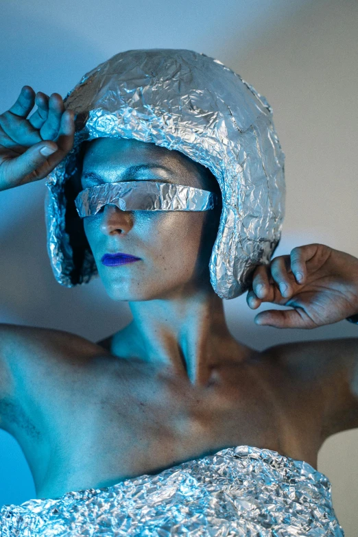 a woman wearing a silver dress and a silver helmet, inspired by hajime sorayama, unsplash, ultraviolet photography, covered in bandages, in a space cadet outfit, solarised