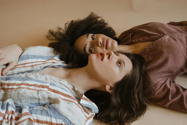 a couple of women laying on top of a bed, trending on pexels, renaissance, brown curly hair, thumbnail, looking from shoulder, lesbian