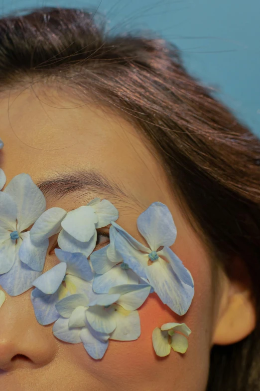 a woman with flowers painted on her face, an album cover, inspired by Elsa Bleda, trending on pexels, aestheticism, pastel blue, japanese, close up photograph, flowers covering eyes