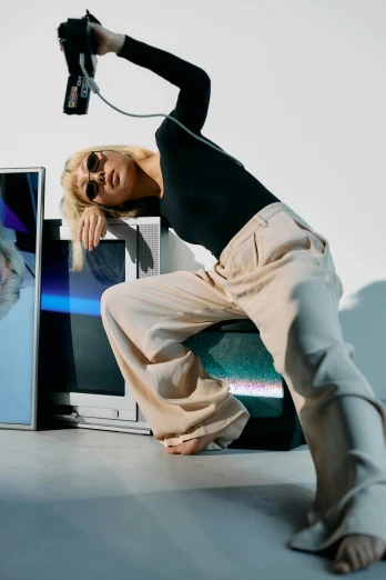 a woman sitting on a chair in front of a television, inspired by Wang E, futuristic tech wear, baggy pants, shot with sony alpha, with square glasses