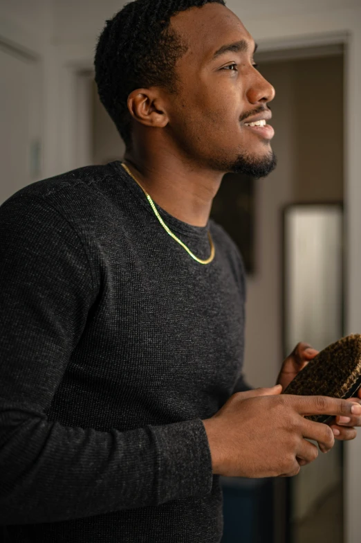 a man holding a brush and comb in his hand, an album cover, inspired by Theo Constanté, trending on pexels, happening, wearing a black sweater, mkbhd, side profile view, holding a snake