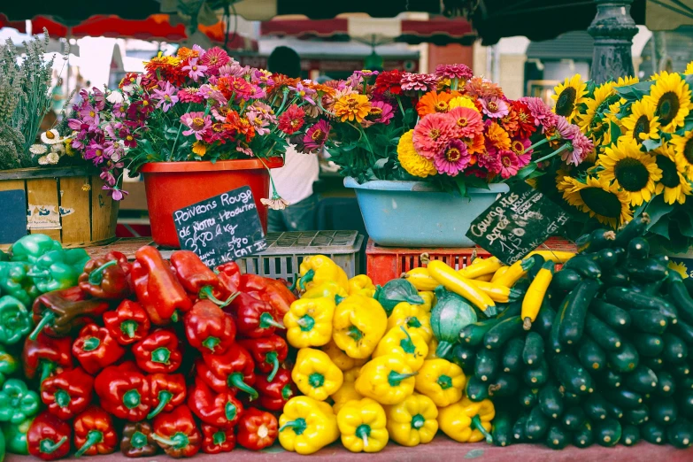 a table topped with lots of different types of vegetables, a photo, by Julia Pishtar, brightly colored flowers, colored market stand, conde nast traveler photo, yellow and red