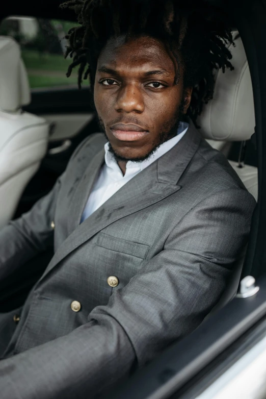 a man in a suit sitting in a car, an album cover, inspired by Willian Murai, pexels contest winner, chief keef, handsome young man, grey skin, david uzochukwu