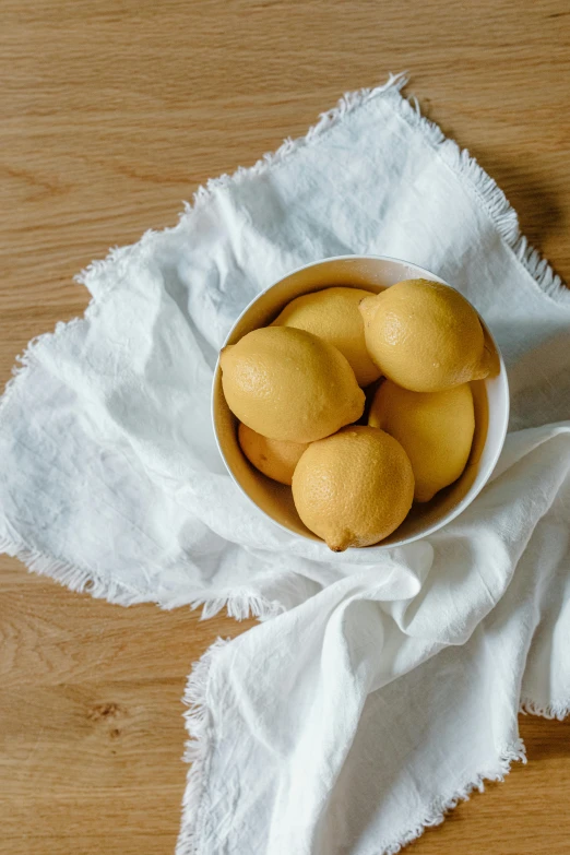 a bowl of lemons sitting on top of a white napkin, detailed product image, soft chin, petite, no crop