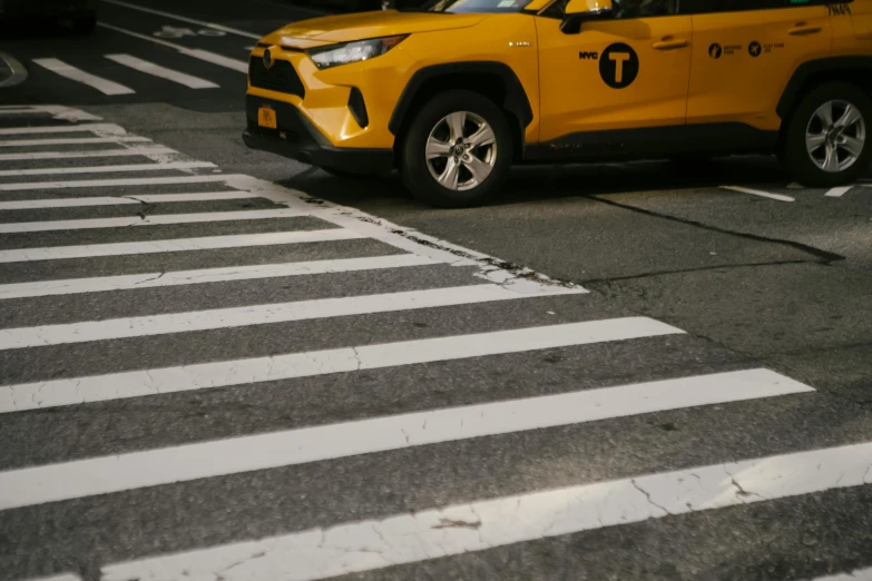 a yellow taxi driving down a street next to a crosswalk, by Carey Morris, pexels contest winner, square, ny, tiger stripes, shot on canon eos r5