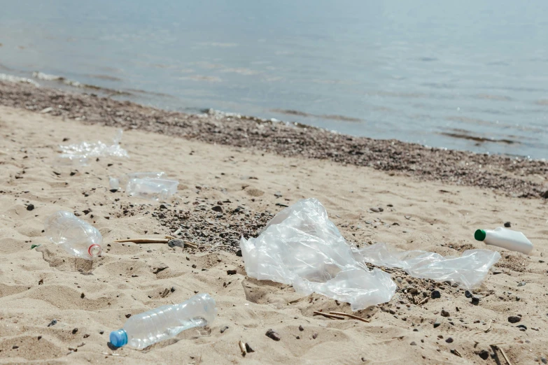 a bunch of plastic bottles sitting on top of a sandy beach, by Matija Jama, pexels contest winner, bags on ground, hidden message, tansparent water, promo image