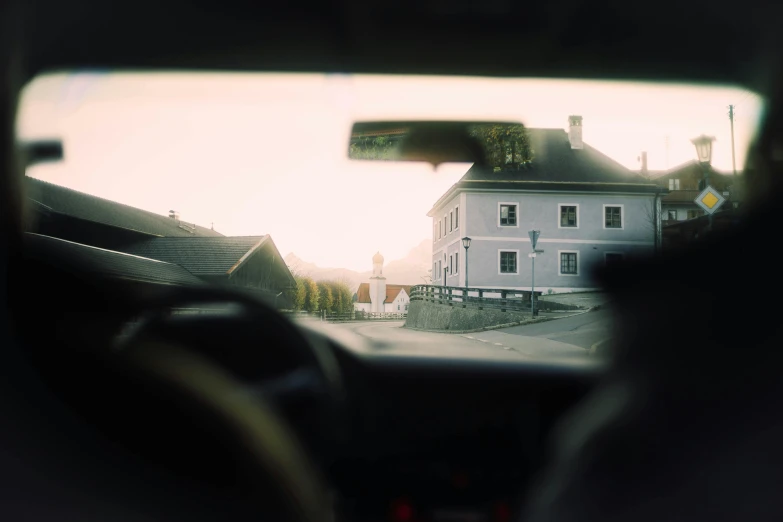 a view of a house through a car window, a picture, by Tobias Stimmer, unsplash, happening, medium format. soft light, austrian architecture, small village, overexposed photograph