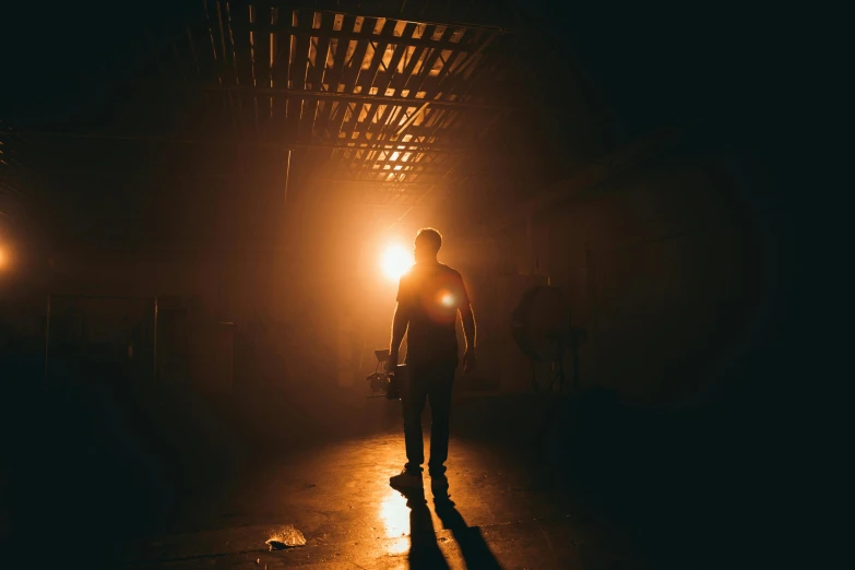 a man standing in the dark holding a skateboard, pexels contest winner, light and space, stood in a factory, eerie back light, theatrical lighting, search lights