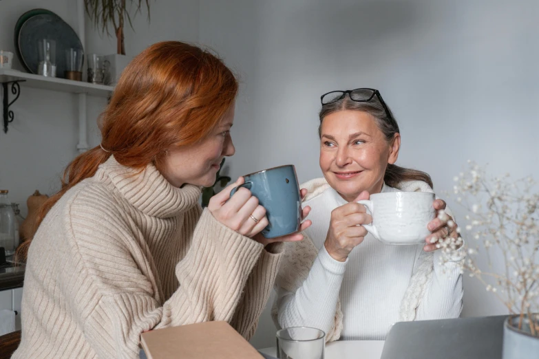 two women sitting at a table with cups of coffee, pexels contest winner, avatar image, middle age, woman holding another woman, high resolution image