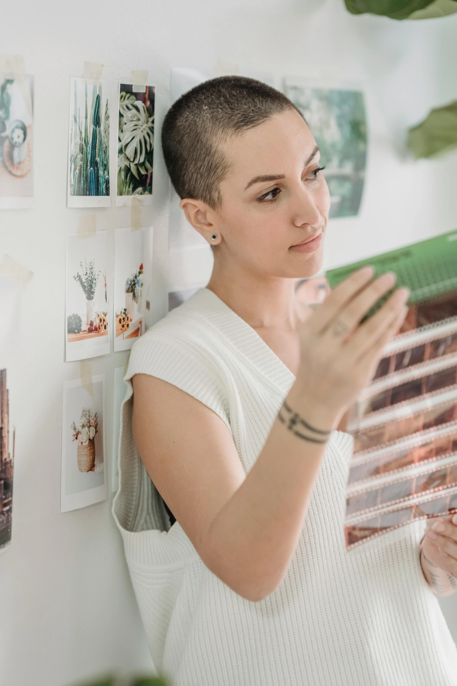 a woman standing in front of a wall holding a book, a picture, pexels contest winner, buzz cut hair, in her room, magazine collage, profile image