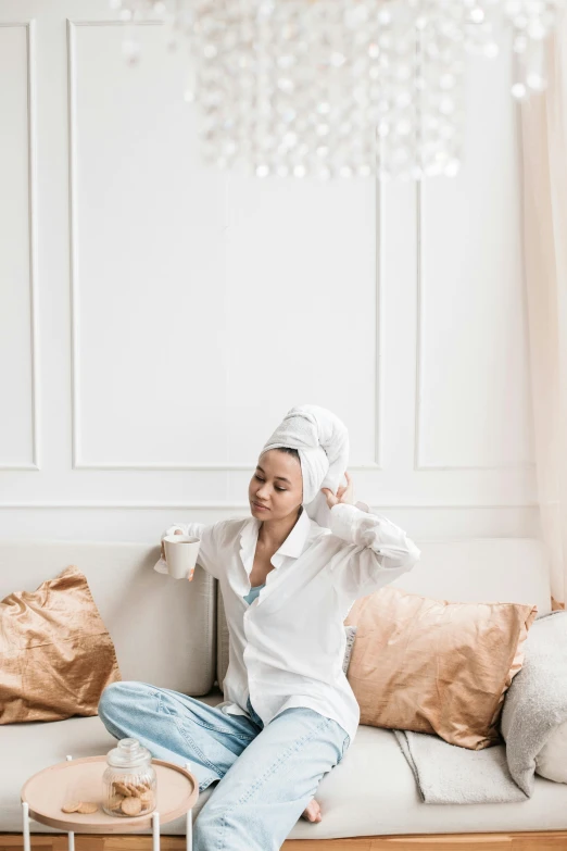 a woman sitting on a couch in a living room, by Julia Pishtar, trending on pexels, hurufiyya, wearing a white bathing cap, bathrobe, her hair is tied above her head, hijab