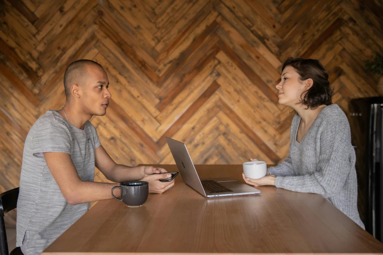 a man and a woman sitting at a table with a laptop, by Jessie Algie, pexels contest winner, sitting on a mocha-colored table, npc talking, lachlan bailey, facing each other