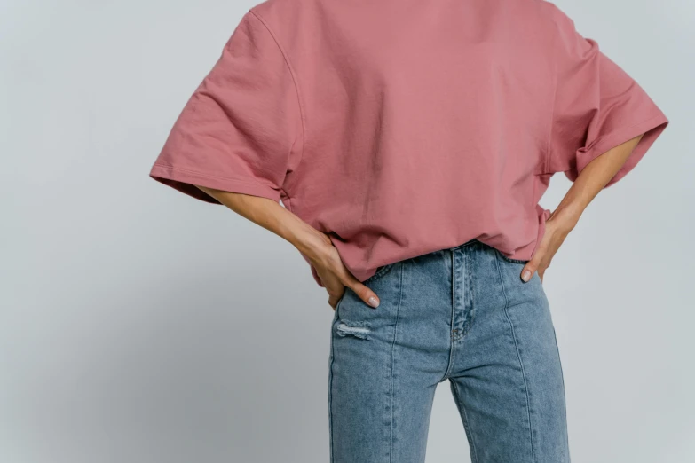 a woman standing with her hands in her pockets, inspired by Jean Hey, trending on pexels, happening, cropped wide sleeve, faded pink, product photo, baggy