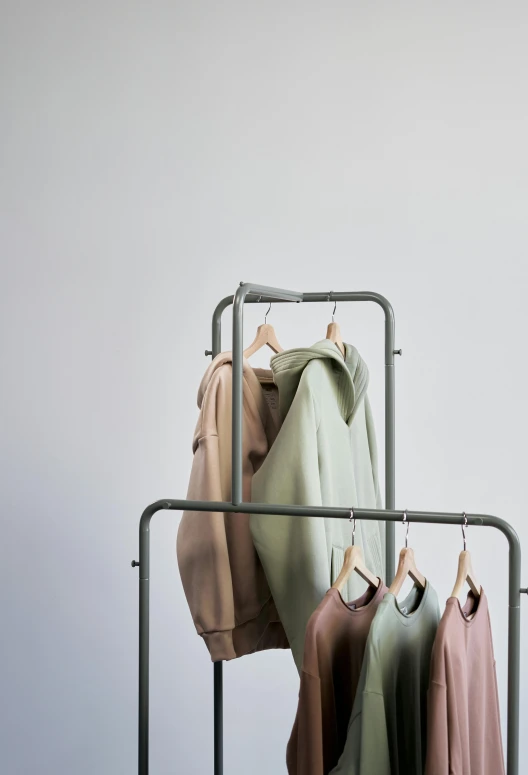 clothes hanging on a rack in front of a white wall, by Caro Niederer, trending on unsplash, pastel green, model エリサヘス s from acquamodels, muted browns, product display