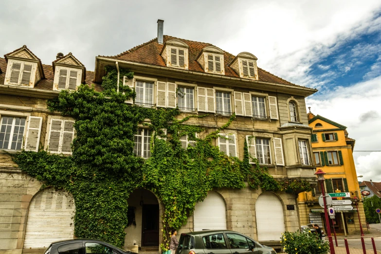 a couple of cars that are parked in front of a building, inspired by Albert Paris Gütersloh, pexels contest winner, vine covered, swiss architecture, green vines, slide show