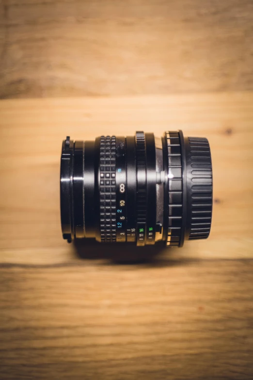 a camera lens sitting on top of a wooden table, a tilt shift photo, by Adam Manyoki, unsplash, photorealism, hasselblad medium format, 1/1250s at f/2.8, 2 5 mm portra, hasselblade shot