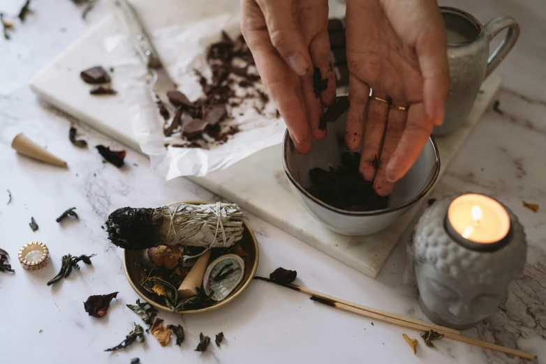 a close up of a person putting something in a cup, a still life, by Julia Pishtar, trending on pexels, dried herbs, ashes crystal, robed figures sat around a table, hands pressed together in bow