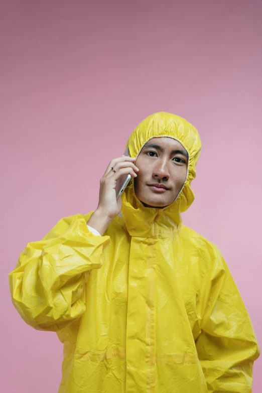 a man in a yellow raincoat talking on a cell phone, inspired by Russell Dongjun Lu, pexels, hyperrealism, karim rashid, latex suit and raincoat, asian, genderless