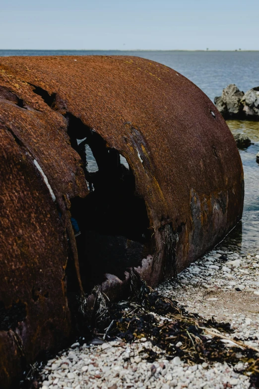 a boat sitting on top of a beach next to the ocean, unsplash, auto-destructive art, sewer pipe entrance, rusted metal texture, portrait photo, o'neill cylinder colony