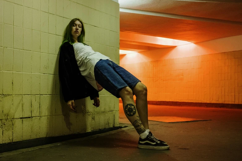 a man leaning against a wall in a parking garage, inspired by Elsa Bleda, unsplash contest winner, hyperrealism, wearing skirt and high socks, billie eilish, wearing shorts and t shirt, at a skate park