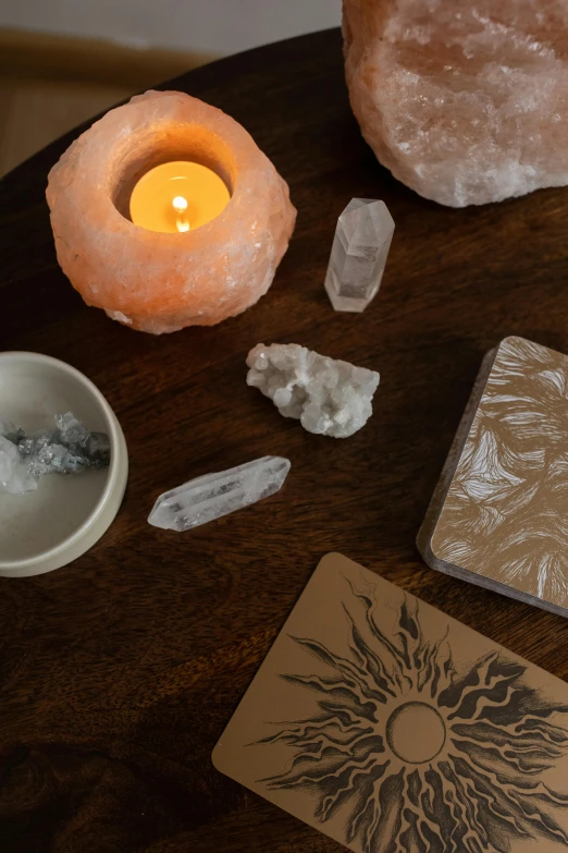 a wooden table topped with crystals and a candle, by Jessie Algie, trending on pexels, light and space, various items, sunstone, lumi, tarot design