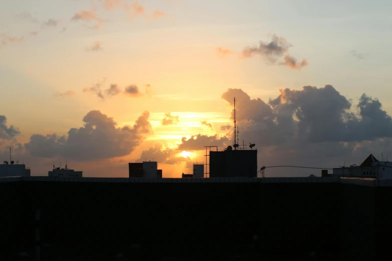 the sun is setting over the city skyline, a photo, by Robbie Trevino, happening, puerto rico, industrial setting, silhouette :7, multiple stories