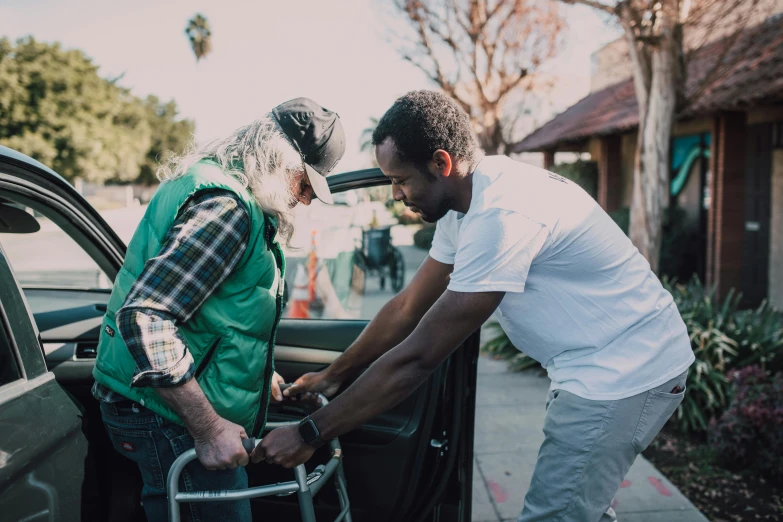 a man helping a woman out of a car, by Meredith Dillman, pexels contest winner, blind brown man, a green, using a exoskeleton, an elderly