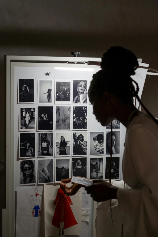 a woman standing in front of a refrigerator, a black and white photo, black arts movement, fashion week backstage, snapshots, light box, dark-skinned