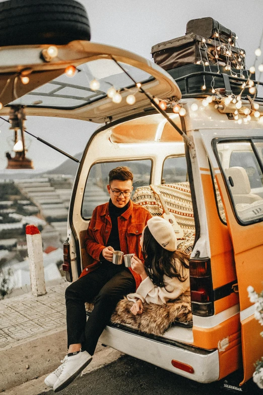 a man and woman sitting in the back of a van, pexels contest winner, maximalism, winter setting, rooftop romantic, on the mountain, sitting in a crane