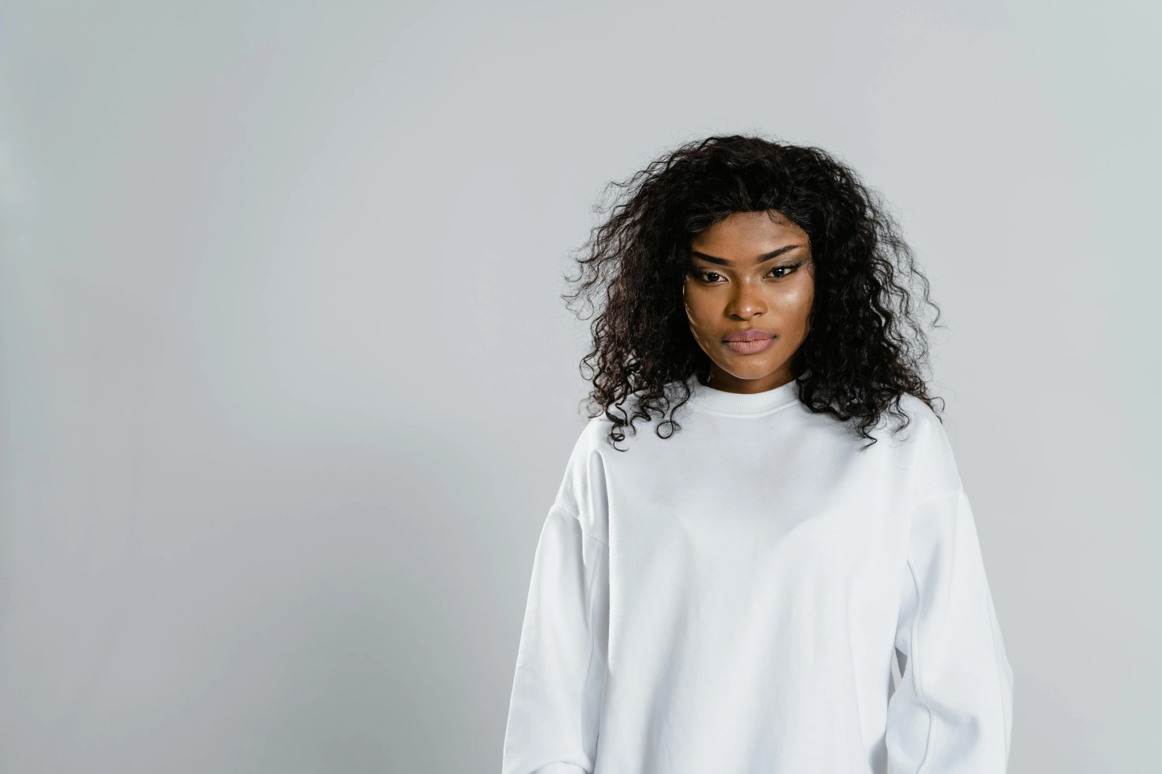 a woman in a white shirt and black pants, trending on pexels, curls, wearing sweatshirt, riyahd cassiem, portrait image