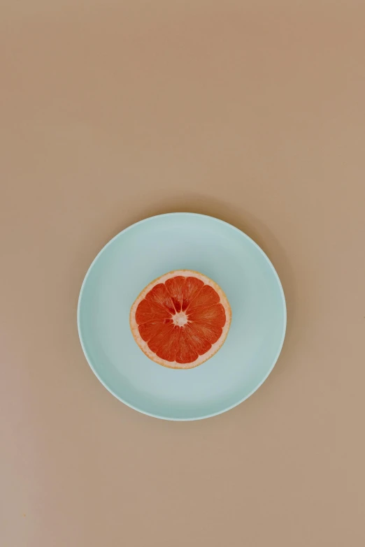 a grapefruit sitting on top of a blue plate, by Carey Morris, trending on pexels, minimalism, thin porcelain, made of food, animation, single light